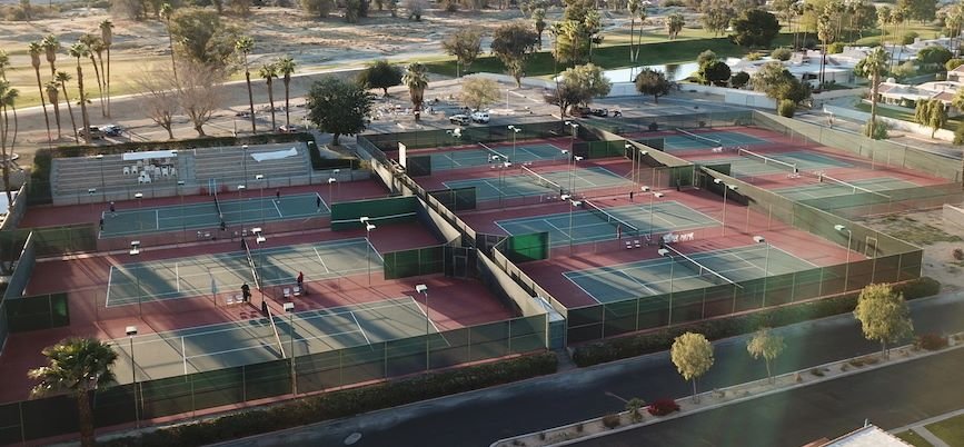 Drone aerial view of the ten hard courts at CC Tennis Club with the Coachella Valley beyond
